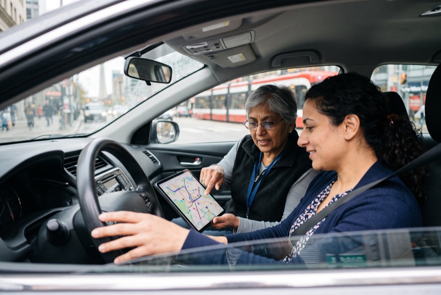 Newcomer driver and instructor reviewing a route on a tablet in downtown Toronto